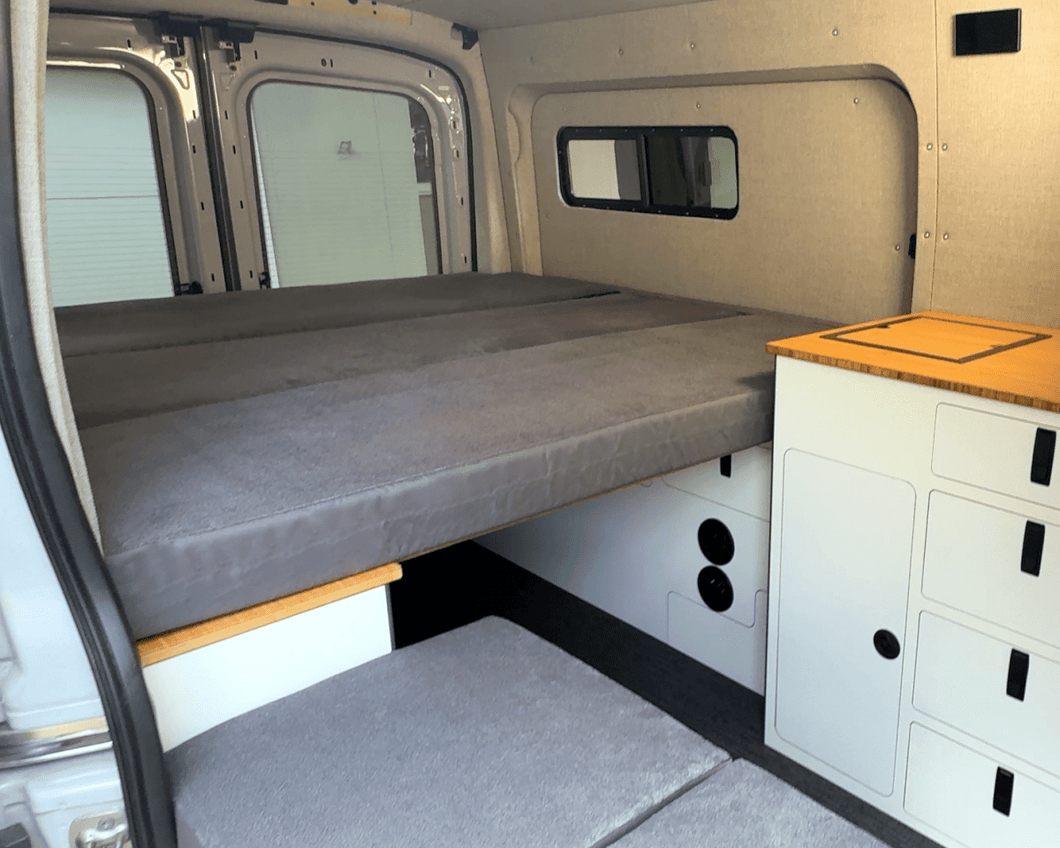 FlexDeck modular van bed system installed between wheel well cabinets