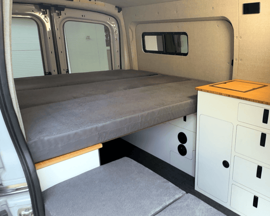 FlexDeck modular van bed system installed between wheel well cabinets